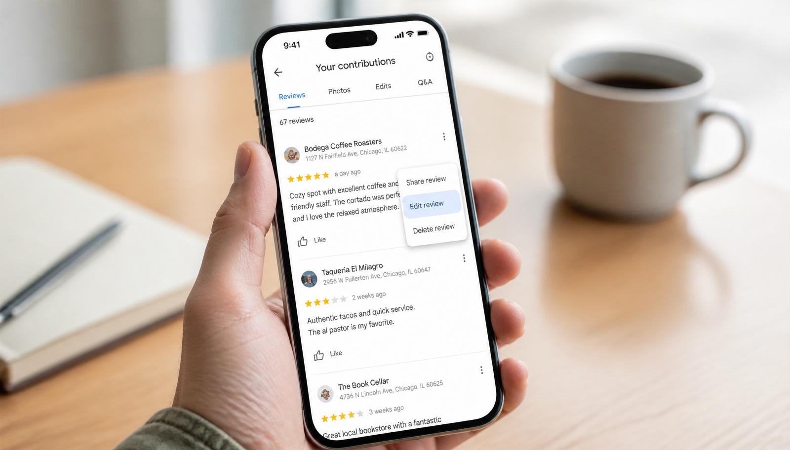Hand holding a phone showing the Google Maps Your contributions screen with a review's three-dot menu open and Edit review highlighted